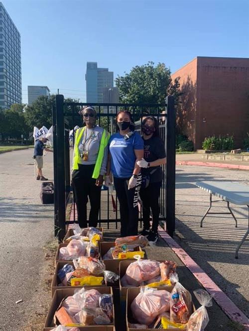 3 workers stand near a fence with bags of supplies 